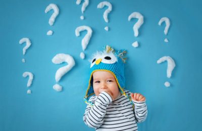 little boy lying on blue blanket with lots of question marks