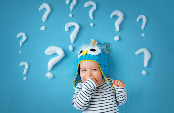 little boy lying on blue blanket with lots of question marks